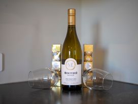 A wine bottle with glasses and chocolates at Mustering - Te Anau Holiday Home Te Anau