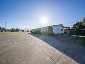 An outdoor view of a house with a driveway and grass at Mustering - Te Anau Holiday Home, Te Anau