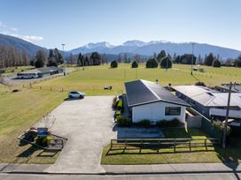 A parking lot with a building and mountains in the background at Dusky Mustering Unit - Te Anau Holiday Home Te Anau