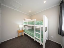 A bedroom with a bunk bed and a side table at Dusky Hunting Unit - Te Anau Holiday Home Te Anau