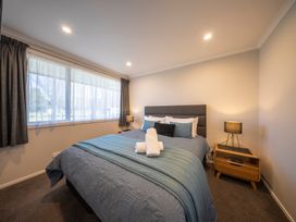 A bedroom with a bed and nightstand at Dusky Hunting Unit - Te Anau Holiday Home