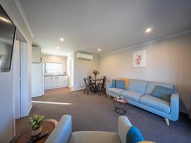 A living room with a couch, table, and kitchen at Dusky Hunting Unit - Te Anau Holiday Home in Te Anau