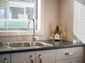 A kitchen with a sink and a bottle of wine at Dusky Hunting Unit - Te Anau Holiday Home in Te Anau