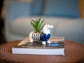 A ceramic dog figure with a plant on a magazine in a living room at Dusky Hunting Unit - Te Anau Holiday Home Te Anau