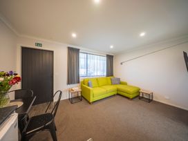 A living room with a green couch and a door at Fishing - Te Anau Holiday Home in Te Anau