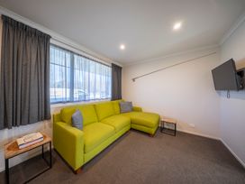 A living room with a green sofa and television at Fishing - Te Anau Holiday Home, Te Anau