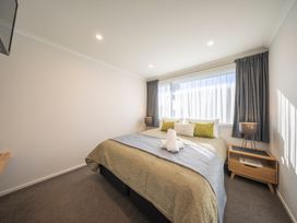 A bedroom with a bed, nightstand, and lamp at Fishing - Te Anau Holiday Home, Te Anau