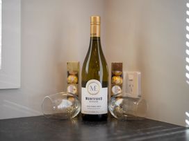 A wine bottle and glasses next to chocolates at Hunting - Te Anau Holiday Home in Te Anau
