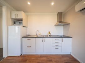 A kitchen with appliances including a refrigerator and microwave at Dusky Rugby Unit - Te Anau Holiday Home Te Anau