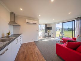 A living room with a kitchen area and dining table at Dusky Rugby Unit - Te Anau Holiday Home Te Anau