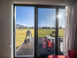 A living room with a view of a garden and grill at Dusky Rugby Unit - Te Anau Holiday Home Te Anau