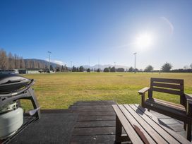 An outdoor area with a barbecue and bench overlooking a rugby field at Dusky Rugby Unit - Te Anau Holiday Home Te Anau