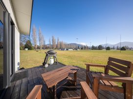 An outdoor area with wooden furniture and a grill at Dusky Rugby Unit - Te Anau Holiday Home Te Anau