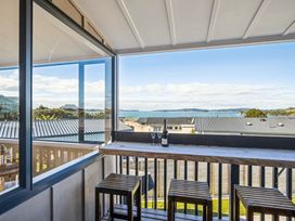A balcony view with glasses and a bottle at Matakana Holiday Home in Warkworth