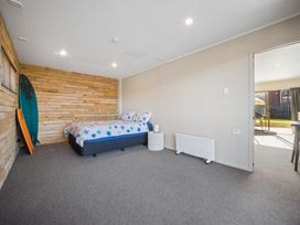 A bedroom with a bed and surfboard at Matakana Holiday Home in Warkworth