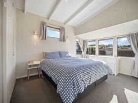 A bedroom with a bed and windows at Matakana Holiday Home in Warkworth