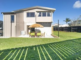 An outdoor area with a table and chairs under an umbrella at Matakana Holiday Home Warkworth