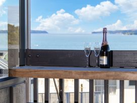 A balcony with a champagne bottle and glasses overlooking the ocean at Matakana Holiday Home in Warkworth