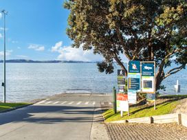 A road leading to water with signs and a tree at Matakana Holiday Home in Warkworth