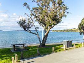 A view of water with a tree and bench at Matakana Holiday Home in Warkworth