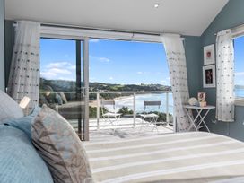 A bedroom with a view of the beach and a small table and chairs at Langs Beach Holiday Home, Langs Beach
