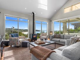 A living room with a fireplace and windows overlooking the beach at Langs Beach Holiday Home in Langs Beach