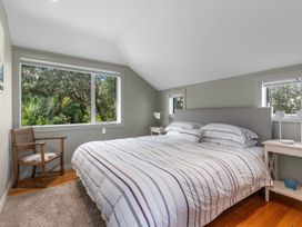 A bedroom with a bed and a chair at Langs Beach Holiday Home in Langs Beach