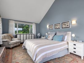 A bedroom with a bed and armchair at Langs Beach Holiday Home in Langs Beach