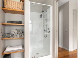 A bathroom with a shower and towels on shelves at Langs Beach Holiday Home in Langs Beach