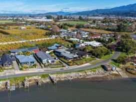 An aerial view of houses and farmland near water at Roy-Al Retreat - Riwaka in Riwaka