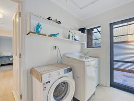 A laundry room with a washing machine and cleaning supplies at Roy-Al Retreat - Riwaka Holiday Home Riwaka