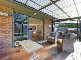 An outdoor patio with a wooden table and chairs at Roy-Al Retreat - Riwaka Holiday Home in Riwaka