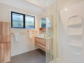 A bathroom with a shower, sink, and storage cabinet at Roy-Al Retreat - Riwaka Holiday Home in Riwaka
