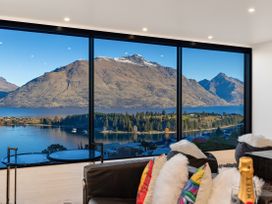 A living room with large windows overlooking mountains and a lake at Alpine Haven - Queenstown Villa in Queenstown