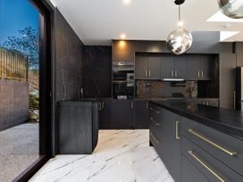 A kitchen with cabinets, a sink, and a window at Alpine Haven - Queenstown Villa, Queenstown