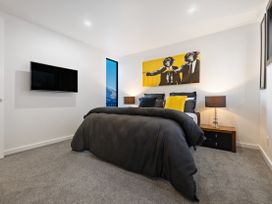 A bedroom with a bed, lamps, and a television at Alpine Haven - Queenstown Villa in Queenstown