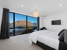 A bedroom with a large window overlooking mountains at Alpine Haven - Queenstown Villa