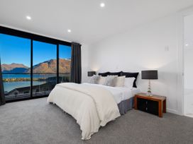 A bedroom with a bed and large windows overlooking a lake at Alpine Haven - Queenstown Villa, Queenstown