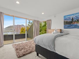 A bedroom with a bed and dresser at Alpine Horizon - Queenstown Holiday Home in Queenstown