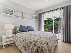 A bedroom with a bed and nightstand at Mangawhai Holiday Home Mangawhai