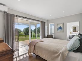A bedroom with a bed and windows at Mangawhai Holiday Home Mangawhai