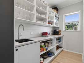 A kitchen with shelves of dishes and a sink at Mangawhai Holiday Home in Mangawhai