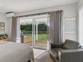 A bedroom with a bed and a chair at Mangawhai Holiday Home in Mangawhai