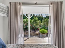 A view from a bedroom window showing plants and a deck at Mangawhai Holiday Home in Mangawhai