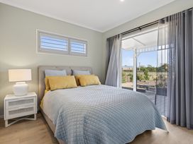 A bedroom with a bed near a door and windows at Mangawhai Holiday Home in Mangawhai