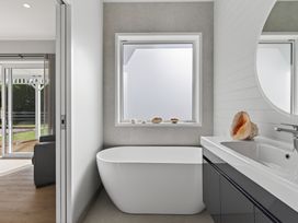 A bathroom with a tub and sink at Mangawhai Holiday Home in Mangawhai