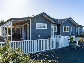 An outdoor view of a house with a porch and planters at Mangawhai Holiday Home in Mangawhai