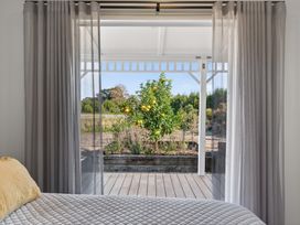 A bedroom with a view of a tree in the garden at Mangawhai Holiday Home Mangawhai