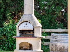 A pizza oven with wood storage and a barrel at Mangawhai Holiday Home in Mangawhai