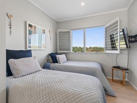 A bedroom with two beds and a television on the wall at Mangawhai Holiday Home in Mangawhai